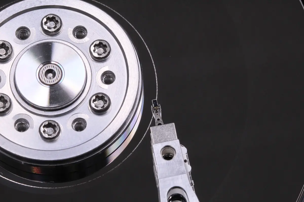 Makro-Nahaufnahme des Spindelmotors einer 3,5-Zoll-Festplatte mit einem Klemmring mit sechs Torx-Schrauben und dem Kopfarm rechts