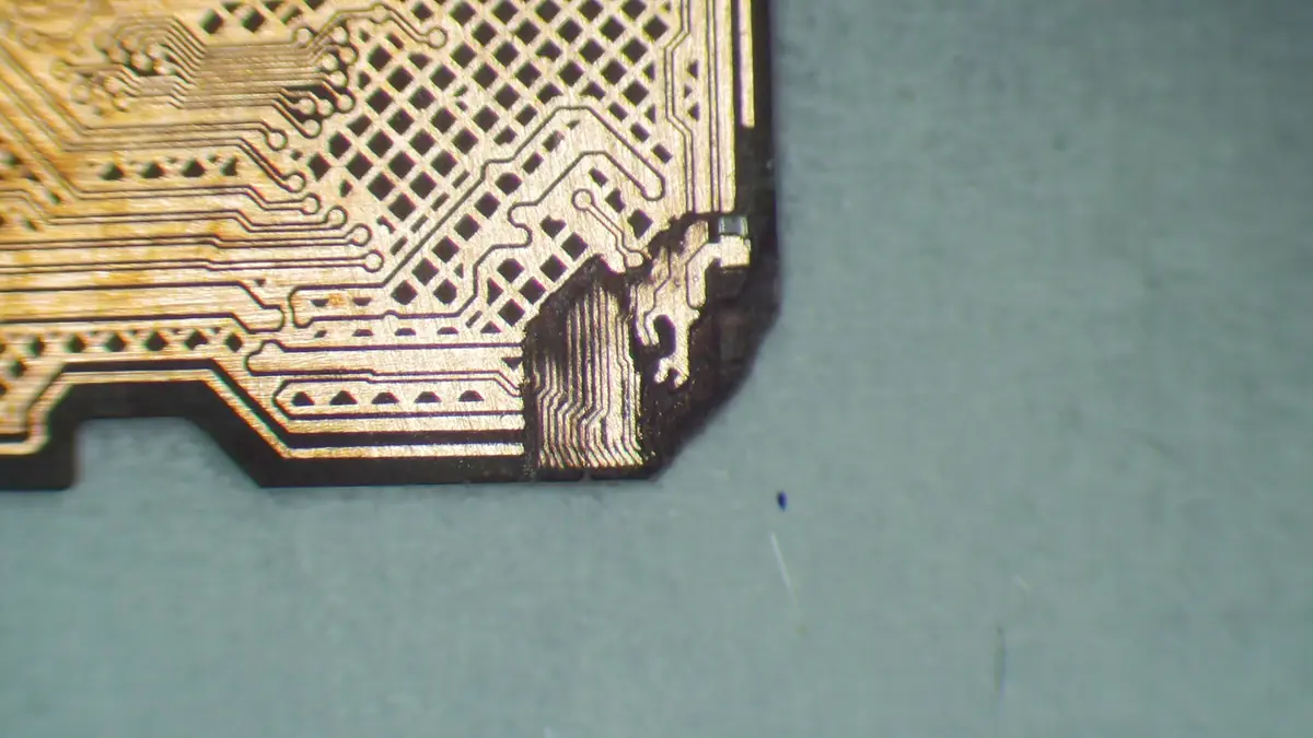 Detail der Leiterbahnen der microSD-Karte unter dem Mikroskop — sichtbar unterbrochene Bahnen nach mechanischer Beschädigung der Ecke
