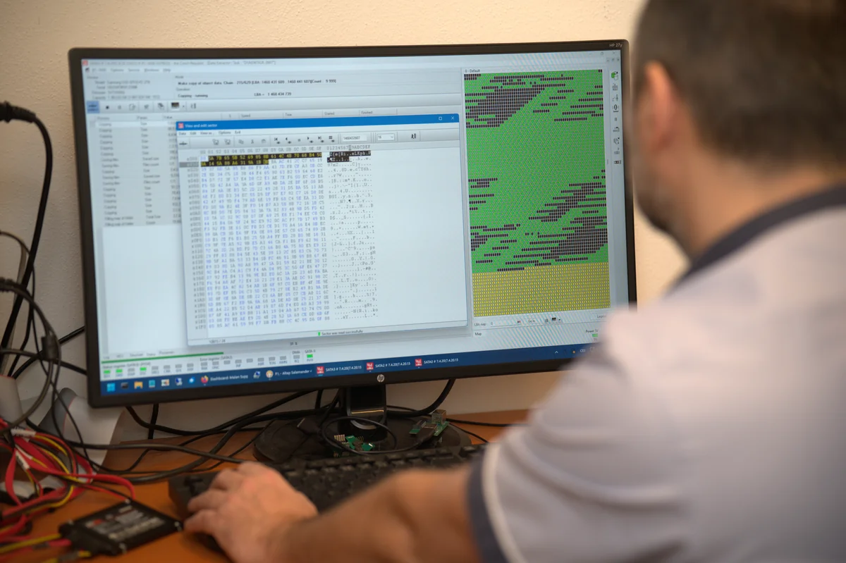 An ITHOPE technician watches the progress of a disk clone in PC-3000 on an HP monitor — a hex editor and a sector map with faults.