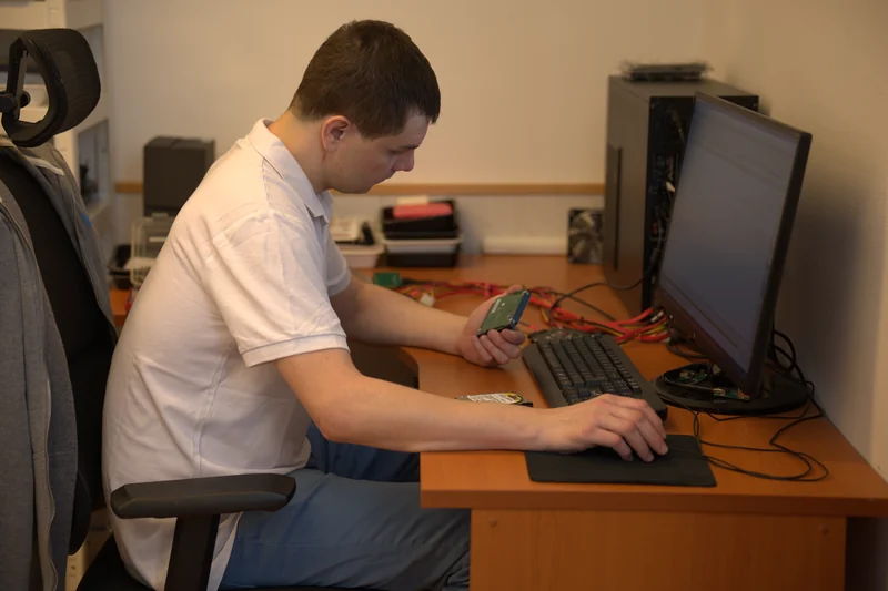 Technik drží 3.5″ pevný disk u diagnostického PC v servisní dílně